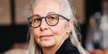 Older woman gives a knowing, direct look, the quiet confidence of someone who's seen decades Gen Z can't imagine.