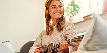 woman relaxing calming down playing guitar at home