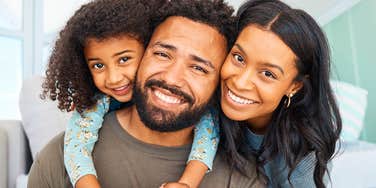 millennial parents smiling alongside their daughter