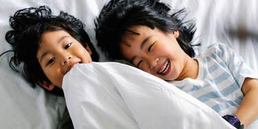 siblings sharing a bed laughing playing together