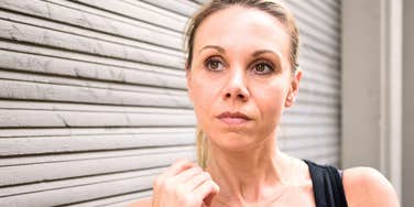 woman looks suspiciously off to the side by a metal garage door
