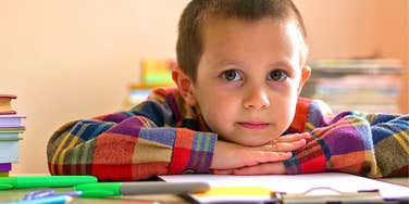 grade-school age boy looking thoughtful at a table