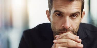 man who looks lonely sits alone with hands clasped