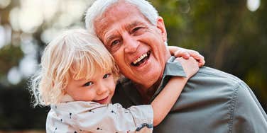 grandfather hugging his grandchild smiling