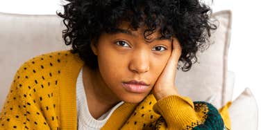 Woman with black dark curly afro hair, sitting on souch at home.