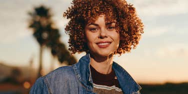 happy woman standing outside letting the universe spoil her