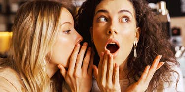 Two friends sitting close together gossiping.