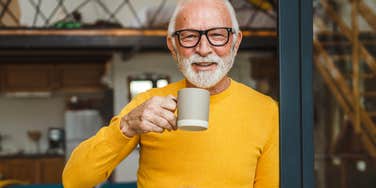 older man who is naturally good at lots of things smiles and sips coffee
