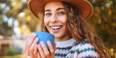 young woman enjoying silence outside in nature holding a mug