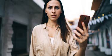 woman who seems lacking emotional control looks angry and holds phone