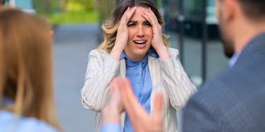 woman feeling stressed and annoyed by coworkers