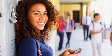 teen girl on her phone in school hallway