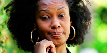 Woman with her hand on her chin, eyebrows raised with pursed lips and a dubious expression.