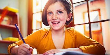 little girl who is a good kid doing her homework and smiling
