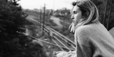 serious woman overlooking train tracks