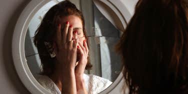 depressed woman looking in broken mirror