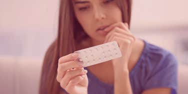 woman holding up birth control pills