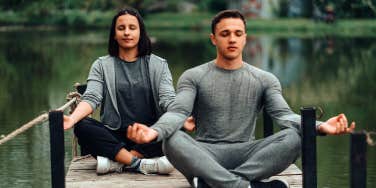 man and woman sitting on dock doing yoga