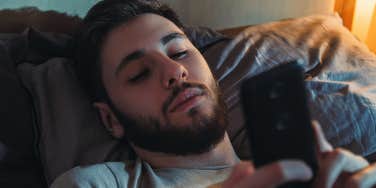 guy laying in bed looking at phone