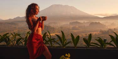 fit woman holding coffee overlooking landscape