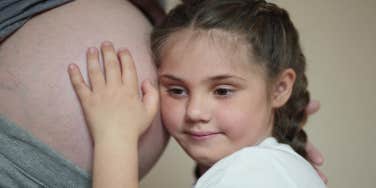 small child holding mother's pregnant belly