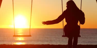 Single or divorced woman alone missing a boyfriend while swinging on the beach at sunset