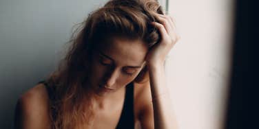 Portrait of young beautiful woman near misted window