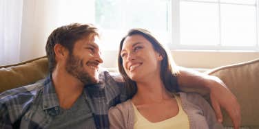 Couple, love and hug or smile at each other on a couch