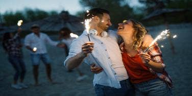 couple on the beach with sparklers for 4th of july date