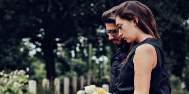 couple looking sadly at a grave