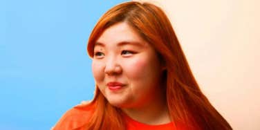 woman with red hair split background blue and beige