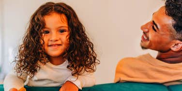 toddler girl smiling next to dad