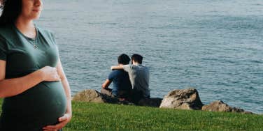 pregnant woman in front of gay couple embracing