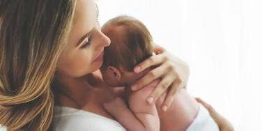 Woman holds a small newborn close to her chest