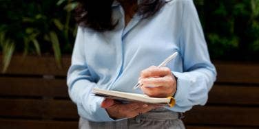 woman in business attire writing in a notebook