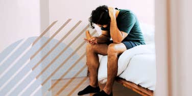 Depressed man sitting on the side of bed rubbing his head 