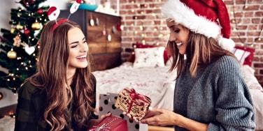 best friends exchanging gifts in front of a christmas tree