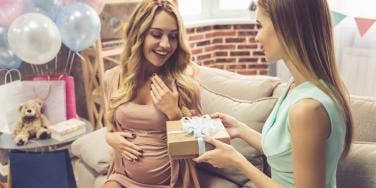 woman giving new mom gift to pregnant friend