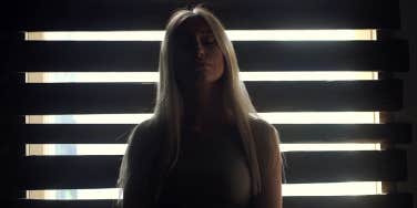 sad woman standing in front of window in dark room