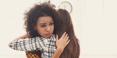 unhappy woman hugging another woman