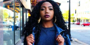 Black woman posing on the sidewalk in denim jacket