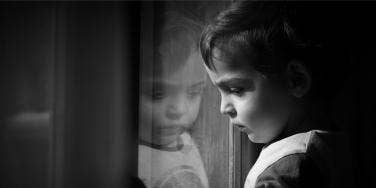 photo of child looking out window in black and white