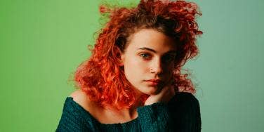 woman with crazy red hair against green background