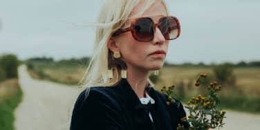 sad woman wearing sunglasses holding flowers