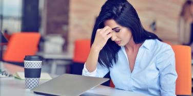 woman stressed head on hand in front of laptop