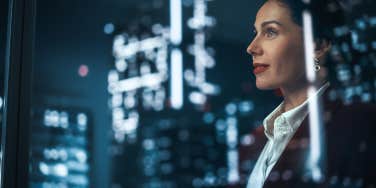 Businesswoman in Stylish Suit Working on Top Floor Office Overlooking Night City
