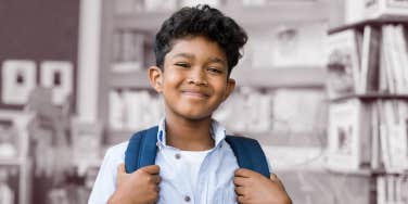 5th grade boy smiling at the camera in a school library