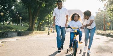 parents teaching daughter to ride a bike