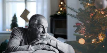Mature man staring at Christmas tree 