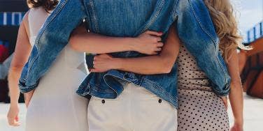 polyamorous couple arms wrapped around back of waist